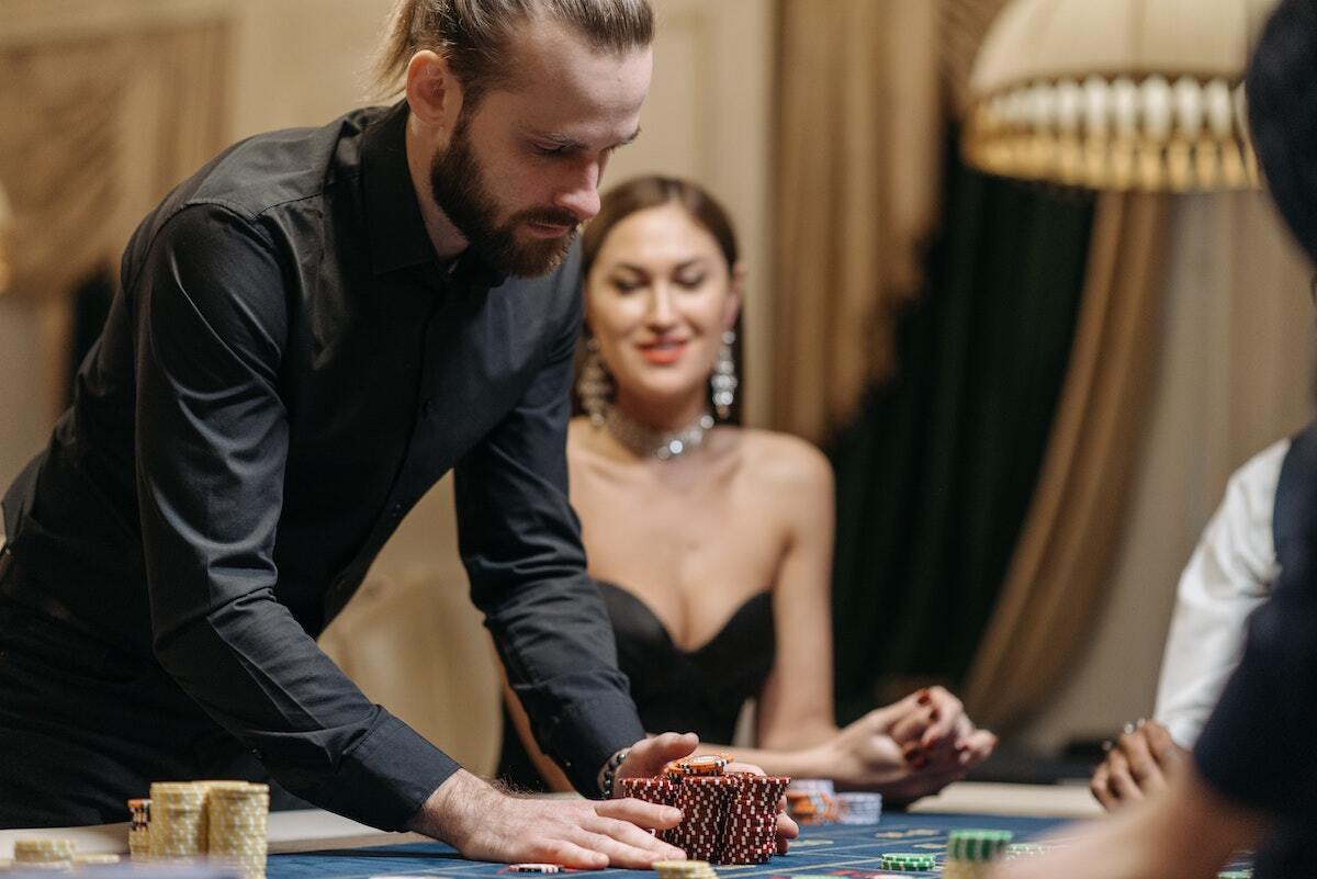 woman at casino table, man rakes in chips at casino table
