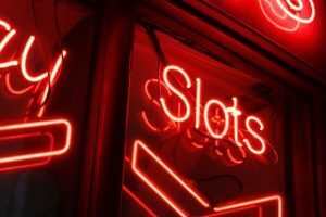 red neon sign that says slots